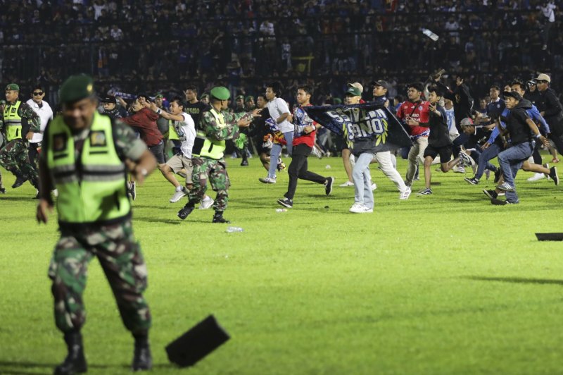 Soccer fans rush onto the field as military personnel try to stop them after a match at Kanjuruhan Stadium in Malang, East Java, Indonesia, on Saturday night. Photo by H. Prabowo/EPA-EFE