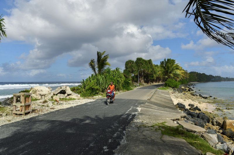 A man rides through the of the narrowest part of the island north of Funafuti, Tuvalu, in 2019. File Photo by Mick Tsikas/EPA-EFE