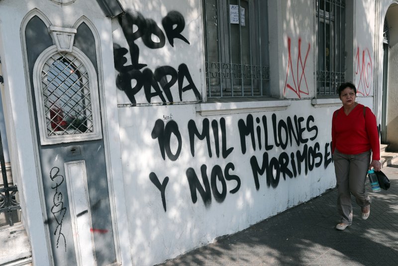 On Friday, a woman walks in front of the Cristo Pobre Church whose facade walls were painted with messages against Pope Francis' visit in Santiago, Chile. Photo by Mario Ruiz/EPA