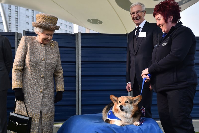 Britain's Queen Elizabeth II looks at a corgi as British actor Paul O'Grady looks on during a visit to the Battersea Dogs and Cats Home in London, Britain, in March 2015. File Photo by EPA