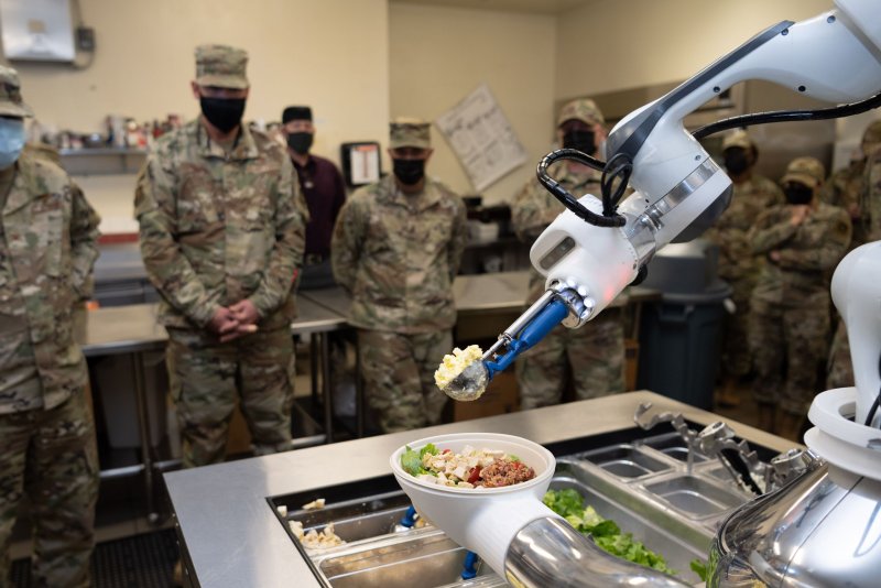 The 60th Mission Support Group leadership watch “Alfred,” an automated food preparation robot, prepare salad at the Travis Air Force Base in California. Photo by Chustine Minoda/U.S. Air Force
