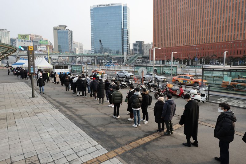 People wait in line to take COVID-19 tests at a makeshift testing center in front of Seoul Station on Sunday. Photo by EPA-EFE/Yonhap