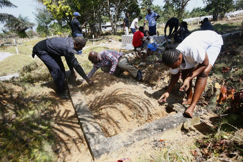 Family members clean the grave of their loved one Wednesday, a suspected Ebola victim in 2015 at the Disco Hill safe burial site in Margibi County, Liberia.&nbsp; File Photo by Ahmed Jallanzo/EPA-EFE