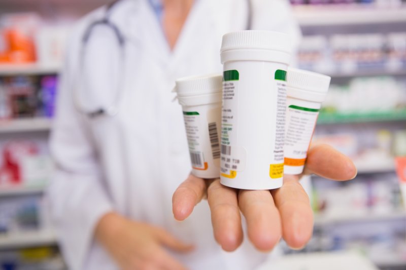 Pharmacist presenting medications on her hand in the pharmacy. Photo by wavebreakmedia/Shutterstock
