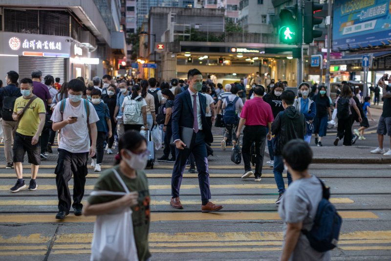 Pedestrians wear masks as they cross an intersection in Wanchai district, Hong Kong on October 14. Despite the recent scrapping of mandatory hotel quarantine upon arriving in the city, restrictions are still in place such as the mandatory wearing of a face mask at all times in public areas among other numerous locations. Cases roses 2% in the past week. Photo by Jerome Favre/EPA-EFE
