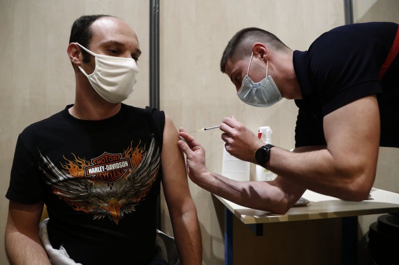 A person receives a dose of the Moderna COVID-19 vaccine by a firefighter at a vaccination centre set up at the fire station of Vailhauques, France, on Thursday. The nation reported a record 104,611 cased Saturday. Photo by Guillaume Horcajuelo/EPA/EFE