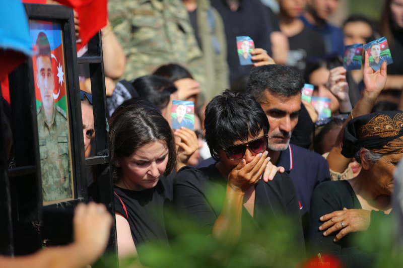 Azeri people stand near the grave of serviceman Sabuhi Ahmadov during mass funerals of servicemen killed during clashes with Armenian troops on the border with Armenia, at the cemetery near Baku, Azerbaijan, Wednesday. Photo by Roman Ismayilov/EPA-EFE