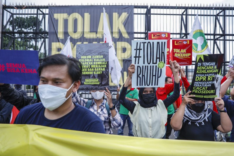 Protesters hold placards rejecting the draft of a new criminal law during a protest outside the parliament building in Jakarta, Indonesia. Photo by Mast Irham/EPA-EFE