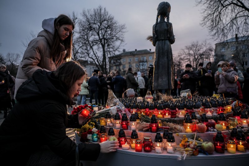 People place candles before the 'Bitter Memory of Childhood' statue by Petro Drozdowsky at the Holodomor Genocide complex of the National Museum in Kyiv, Ukraine, on Saturday. Five people in the capital were injured by a 'massive' Russian drone strike on the eve of the remembrance. Photo by Oleg Petrasyuk/EPA-EFE