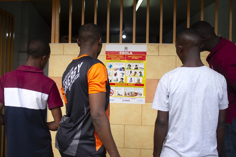 Men look at an Ebola virus disease awareness campaign poster following an outbreak of Ebola in Uganda, in Kampala, Uganda, in late September. Some four months later, and the country has declared the outbreak over. Photo by EPA-EFE