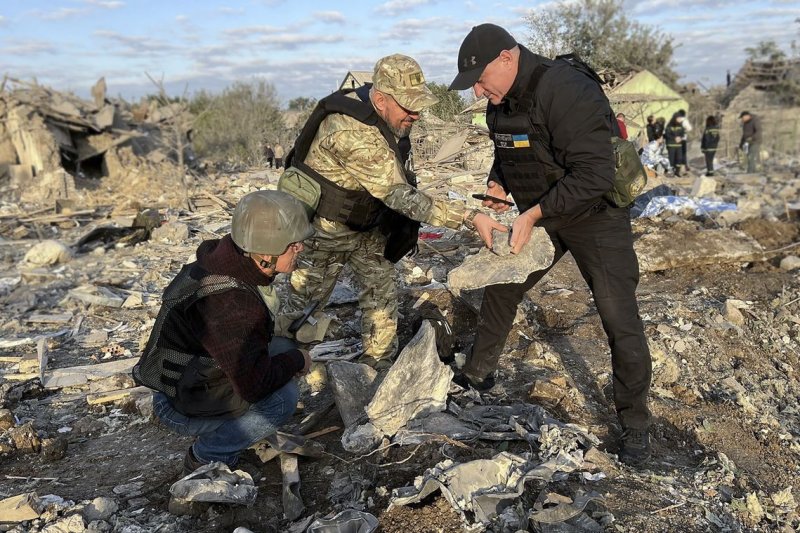 Ukrainian rescuers inspect debris of a missile at the site of shelling in Zaporizhzhia, Ukraine, on Sunday. At least 17 persons were killed and 49 injured. Photo by Ukraine National Police/EPA-EFE